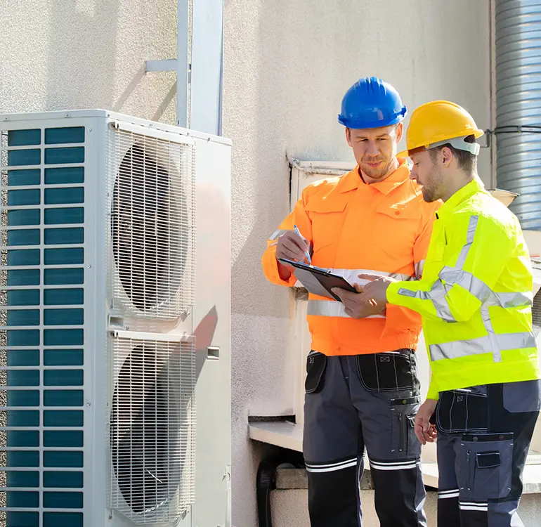 Technicians inspecting rooftop HVAC unit