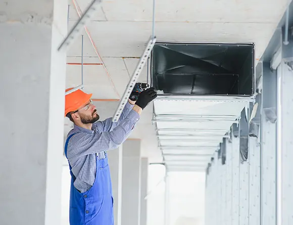 Worker inspecting HVAC ductwork installation