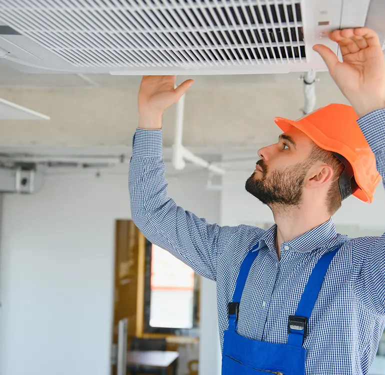 HVAC technician inspecting ceiling unit