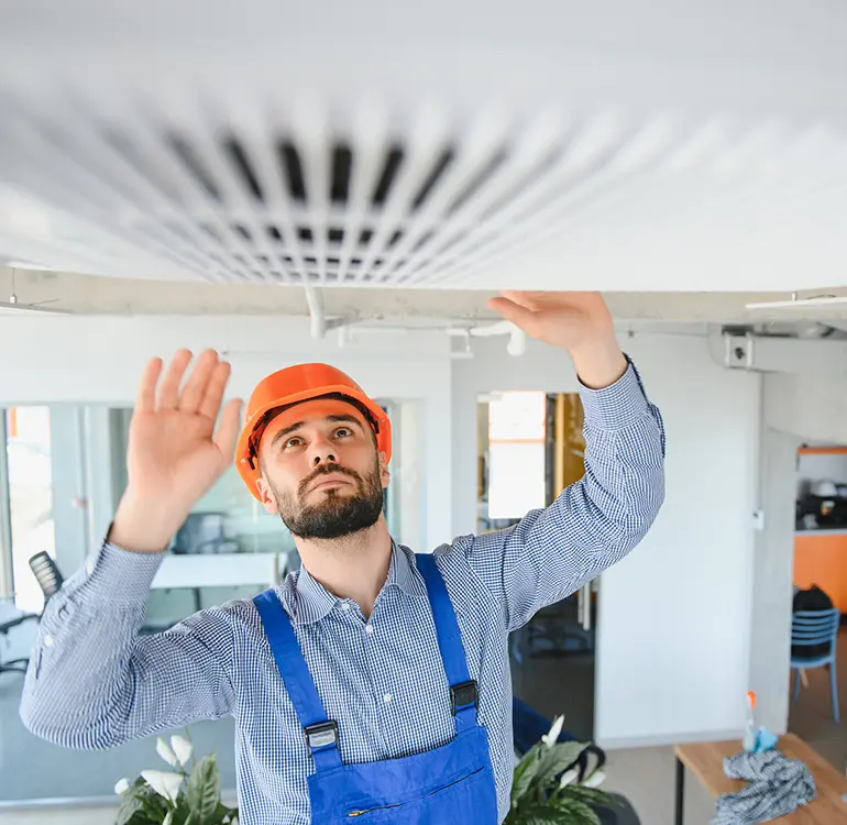 HVAC technician inspecting ceiling vent