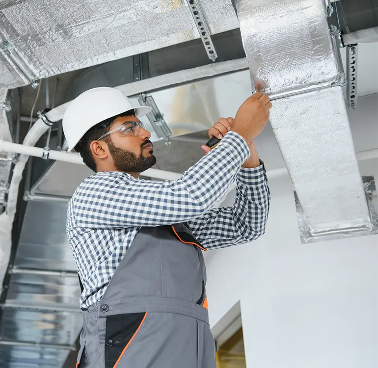 Worker installing HVAC ductwork system