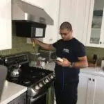 technician inspecting airflow near stove